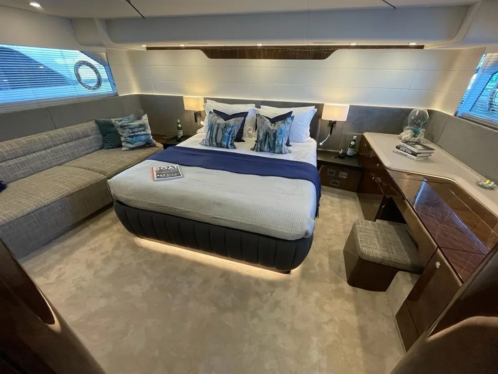 Luxurious boat cabin featuring a double bed, seating area, desk, and decorative items, bathed in soft lighting.
